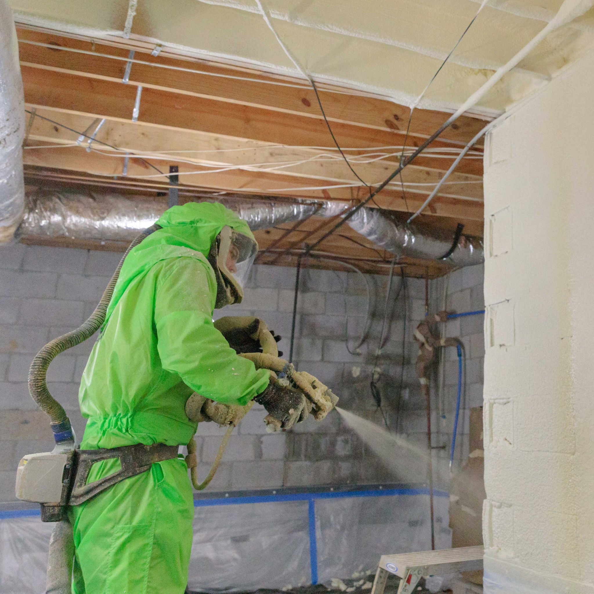 A man installing spray foam in a basement