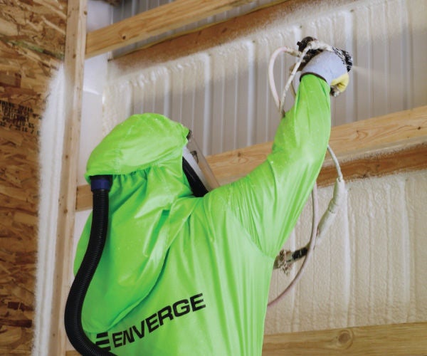 man spraying nexseal spray foam insulation with green enverge jumpsuit
